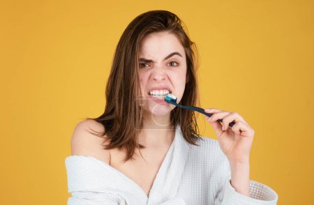 Foto de Mujer joven cepillándose los dientes. Feliz chica divertida cepillarse los dientes sobre un fondo aislado. Hermosa sonrisa amplia de mujer joven con grandes dientes blancos sanos - Imagen libre de derechos