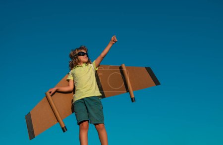 Photo for Boy pilot against a blue sky. Cute dreamer boy playing with a cardboard airplane. Childhood. Fantasy, imagination - Royalty Free Image
