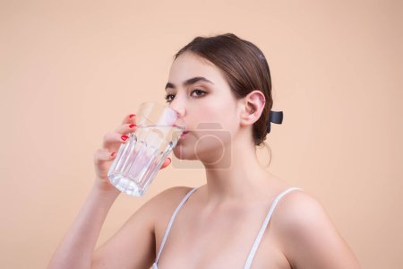 Photo for Woman drinking water, isolated on studio background. Portrait of happy smiling young woman with glass of fresh water. Thirsty girl. Refreshing. Water balance - Royalty Free Image