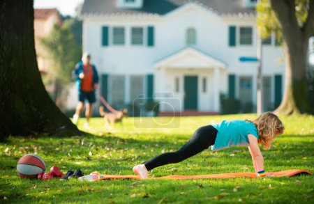 Photo for Kid doing push-ups sport exercises in park. Sport, healhty lifestyle, training, active leisure outdoor. Kid pushing up. Athletic boy is pushing up on the green grass. Sport kids - Royalty Free Image