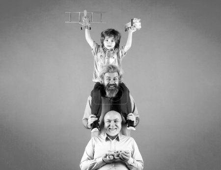 Photo for Fathers day concept. Three different generations ages grandfather father and child son playing with toy plane in studio. Journey travel trip concept. Isolated background - Royalty Free Image