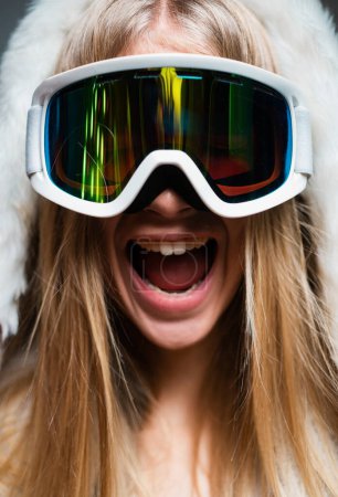 Foto de Emocionada mujer asombrada con gafas de esquí. Primer plano retrato de invierno de la joven chica increíble con gafas de nieve. Cara graciosa - Imagen libre de derechos
