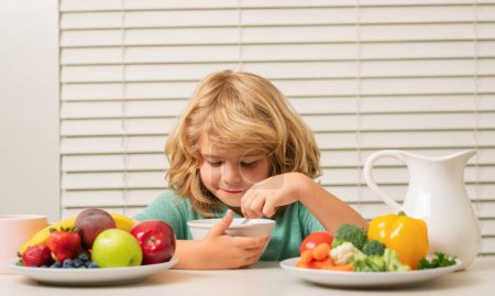 Photo for Schoolchild eating breakfast before school. Portrait of little teen child sit at desk at home kitchen have delicious tasty nutritious breakfast - Royalty Free Image