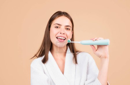 Foto de Cepillo de dientes eléctrico. Mujer joven cepillándose los dientes. Hermosa sonrisa de mujer joven con dientes blancos sanos. Fondo aislado. Primer plano de la mujer joven con cepillo de dientes - Imagen libre de derechos