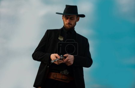 Photo for American cowboy man. Handsome brutal western guy. Sheriff with wild west guns, vintage pistol revolver and marshal ammunition. American western. Wild west with cowboy - Royalty Free Image