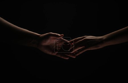 Photo for Two hands reaching toward. Helping hand outstretched for salvation on isolated black background. Close up of man and woman hand touch with fingers - Royalty Free Image