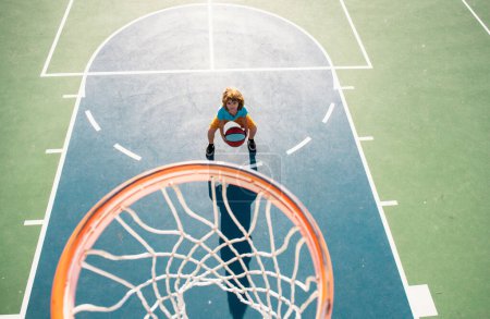 Téléchargez les photos : Vue d'angle du dessus de l'enfant jouant au basket sur l'aire de jeux - en image libre de droit