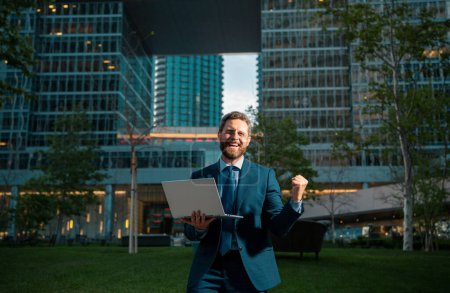 Photo for Excited business man. Business man standing in the the city is happy to succeed in his work. He lifts his arms up - Royalty Free Image