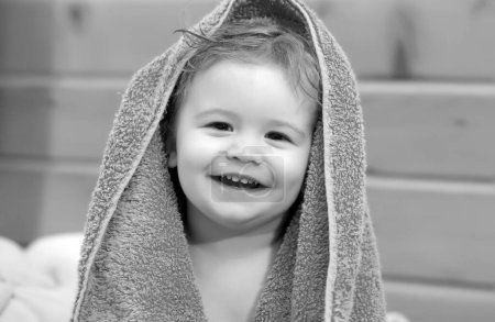 Téléchargez les photos : Portrait d'un heureux bébé riant couvrant le corps sous la serviette après le bain. Gros plan positif enfants visage - en image libre de droit