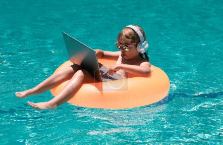 Photo for Child swimming on an inflatable ring with a laptop water pool. Child online study or working on tropical sea beach. Technology for life concept - Royalty Free Image