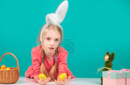 Foto de Linda chica en orejas de conejo en el día de Pascua. Niña sosteniendo huevos pintados - Imagen libre de derechos