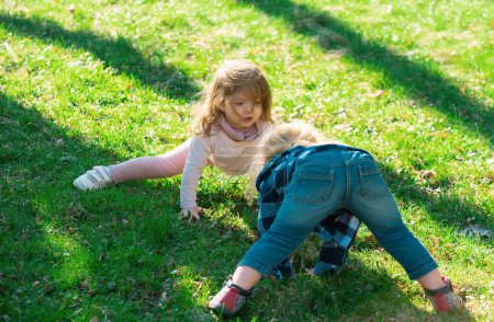 Téléchargez les photos : Children babys playing upside down on green field, summer outdoor kids lifestyle - en image libre de droit