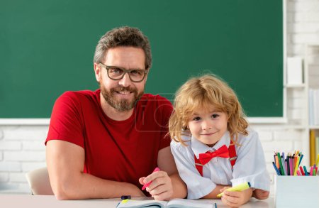 Photo for School teacher and child pupil in classroom. Elementary school boy in classroom on lesson. Teacher explaining to pupil - Royalty Free Image