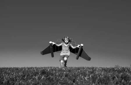 Foto de Pequeño niño juega astronauta o piloto. Niño en el fondo del cielo azul. Niños con alas de papel jetpack sueños. Los niños imaginan sueños de volar. Chico gracioso con mochila de juguete. Éxito, imaginación - Imagen libre de derechos