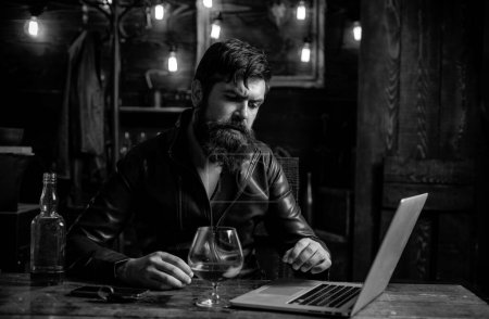 Foto de Un hombre de negocios barbudo con un vaso de whisky. Estresado por el trabajo duro - Imagen libre de derechos