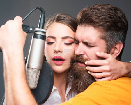 Téléchargez les photos : Couple chanteur chantant rock. Producteur sonore enregistrant une chanson dans un studio de musique. Homme et femme sexy chantant avec microphone de musique - en image libre de droit