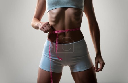 Photo for Slim young woman measuring her thin waist - Royalty Free Image