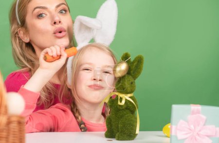 Foto de Semana Santa familiar. Madre e hija pintando huevos. Linda niña está usando orejas de conejo - Imagen libre de derechos