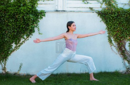 Photo for Yoga, fitness and training. Fit girl in sportswear doing morning yoga. Young fit woman stretching. Sporty young girl doing fitness exercise, healthy life on green grass. Outdoor workout - Royalty Free Image