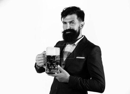 Foto de Un hombre serio con traje clásico bebiendo cerveza. Tipo barbudo en traje de negocios se ve feliz y satisfecho. Retrato del hombre con copa alta de cerveza levantada isoalted en blanco - Imagen libre de derechos