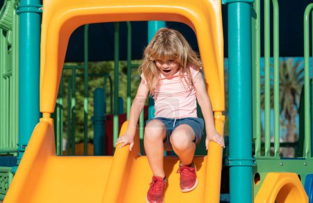 Téléchargez les photos : Cute little kid boy funny while playing on the playground. Summer, childhood, leisure and children concept - en image libre de droit
