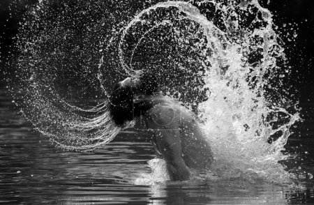 Foto de Hombre barbudo sexy con cabello mojado y barba nadando en agua y gotas. Gay salpicando agua por su cabello mojado y barba en la cara divirtiéndose. Siente la libertad - Imagen libre de derechos