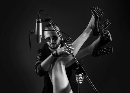 Photo for Sexy singer dj is performing a song with a microphone while recording it in a music studio - Royalty Free Image