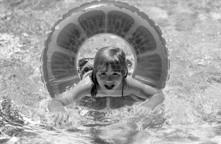 Foto de Niño nadando con anillo de flotador en la piscina. Vacaciones de verano para niños y concepto de vacaciones. Niño feliz con anillo inflable en la piscina. Cara divertida del verano de los niños - Imagen libre de derechos