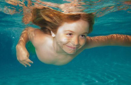 Foto de Niños divertidos juegan y nadan en el agua del mar. Niño nadando bajo el agua en la piscina. Lindo niño nadando bajo el agua en aguas turquesas poco profundas en la playa tropical - Imagen libre de derechos