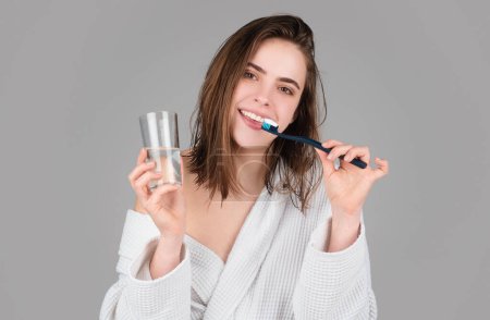 Téléchargez les photos : Jeune femme souriante avec des dents saines tenant une brosse à dents. Des dents humaines. Clinique de soins dentaires. Le gros plan d'une jeune femme se brosse les dents. Brosse à dents avec dentifrice - en image libre de droit