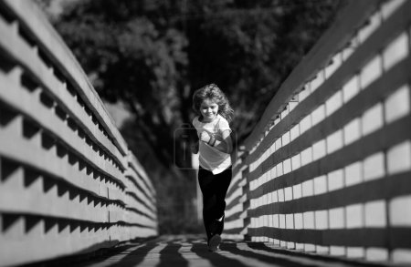 Photo for Child runners run in park. Boy running in the park in summer in nature. Outdoor sports and fitness, exercise and competition learning for kid development - Royalty Free Image