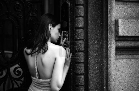 Foto de Timbre de botón de intercomunicación mujer en la entrada del edificio. Vestido joven dama invitada hembra entrar código de la puerta - Imagen libre de derechos
