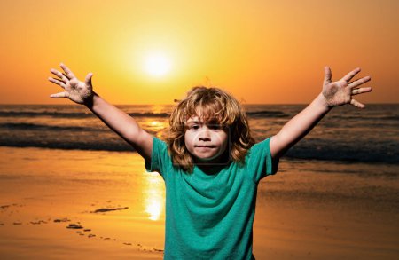 Photo for Kid boy on sunset beach, raised hands. Amazed surprised kids emotions - Royalty Free Image