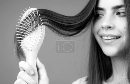 Téléchargez les photos : Gros plan portrait de belle fille heureuse avec des cheveux brillants avec peigne - en image libre de droit