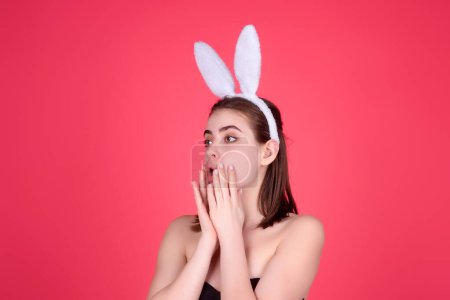 Foto de Easter girl. Young woman wearing Easter bunny ears holding decorative colored eggs on studio background with copy space - Imagen libre de derechos