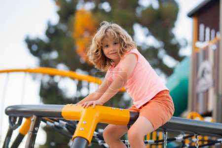 Téléchargez les photos : Cute child boy plays on playground. Kid climbing on playground - en image libre de droit