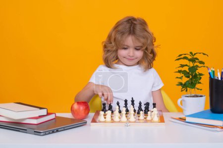 Photo for Kid playing chess. Child thinking near chessboard. Learning and growing children, childgood. Kids early development. Little chess player on yellow isolated studio background - Royalty Free Image