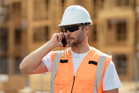 Photo for Hispanic 40s worker builder man on site construction. American middle aged man worker. Worker using phone, builder taking on phone a break from work. Architect with mobile phone - Royalty Free Image