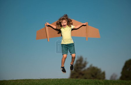 Child boy playing pilot on the sky blue background. Kid dreaming. Child playing with toy jetpack. Kid pilot having fun at park. Portrait of child against summer sky. Travel and freedom concept