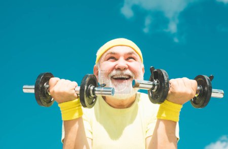 Happy senior man with dumbbell looking at camera. Senior male is enjoying sporty lifestyle. Senior man workout in rehabilitation center