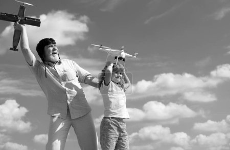 Téléchargez les photos : Grand-père et fils tiennent l'avion et le drone quadricycle contre le ciel. Enfant pilote aviateur rêvant de voler - en image libre de droit