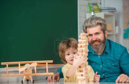 Photo for Happy school kids at lesson. Teachers day. Father and son playing jenga game at home - Royalty Free Image