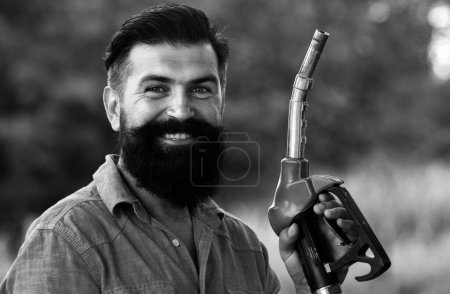 Photo for Man on petrol pump filling nozzles. Gas station. Portrait of bearded man hold fueling nozzle gasoline, fuel pump - Royalty Free Image