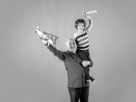 Photo for Child boy and grandfather piggyback with toy plane and wooden truck. Men generation granddad and grandchild - Royalty Free Image