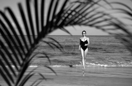 Téléchargez les photos : Jeune femme heureuse courant pieds nus sur la plage. Plage d'été et mer - en image libre de droit