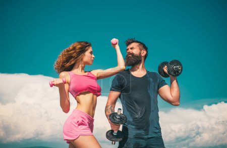 Photo for Couple working out with dumbbell weights. Attractive woman and handsome muscular man are training outdoors. Couple in love on fitness training with Dumbbell on sky outside - Royalty Free Image