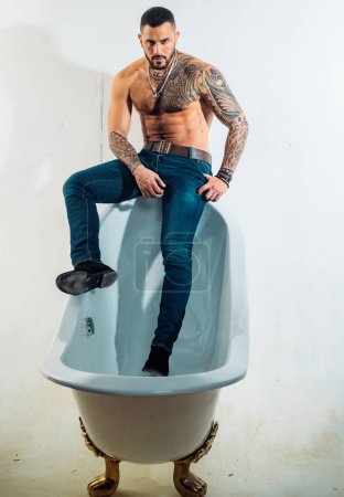 Téléchargez les photos : Dans la baignoire. Homme hispanique barbu avec le torse musclé assis sur le bord du bain. Brutal latino homme relaxant dans le bain. Baignoire spa et jacuzzi
. - en image libre de droit