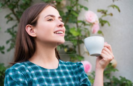 Téléchargez les photos : Belle femme pose avec tasse de café. Joyeux sourire fille boire du café, fond de printemps extérieur - en image libre de droit