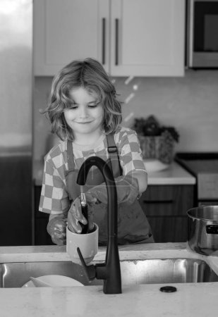 Photo for Dish washing concept. Little housekeeper. Child washing and wiping dishes in kitchen. American kid learning domestic chores at home. Kid cleaning to help parents with housework routine - Royalty Free Image