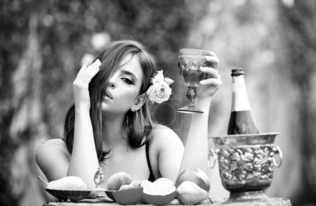 Foto de Mujer sexy con fruta fresca en una mesa en el parque al aire libre. Sensual joven beber champán - Imagen libre de derechos